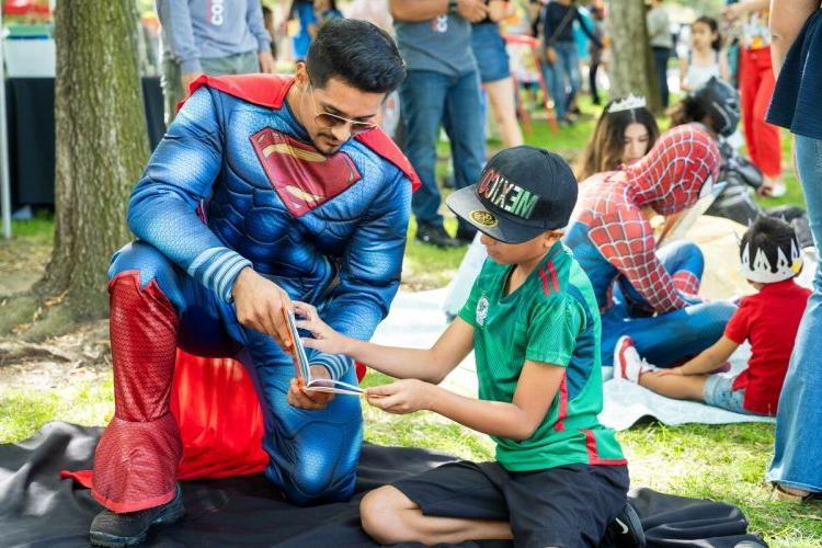 A student with the 社区参与计划 reads to children in Stockton during the annual Family Day at the Park. 