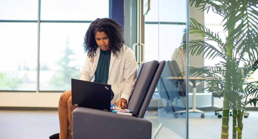 Woman typing on laptop, sitting in a chair